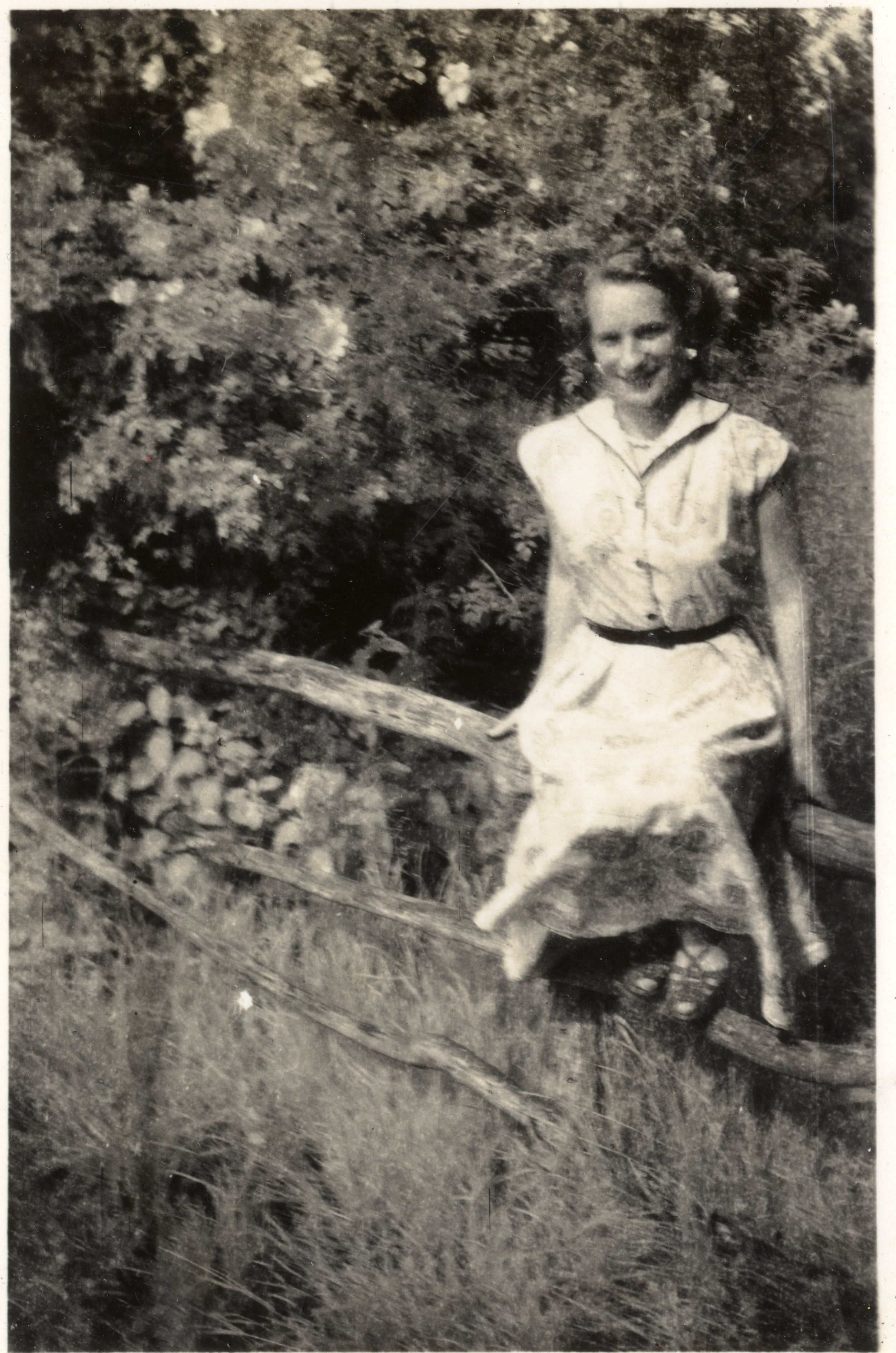 Woman sat on wooden fence.