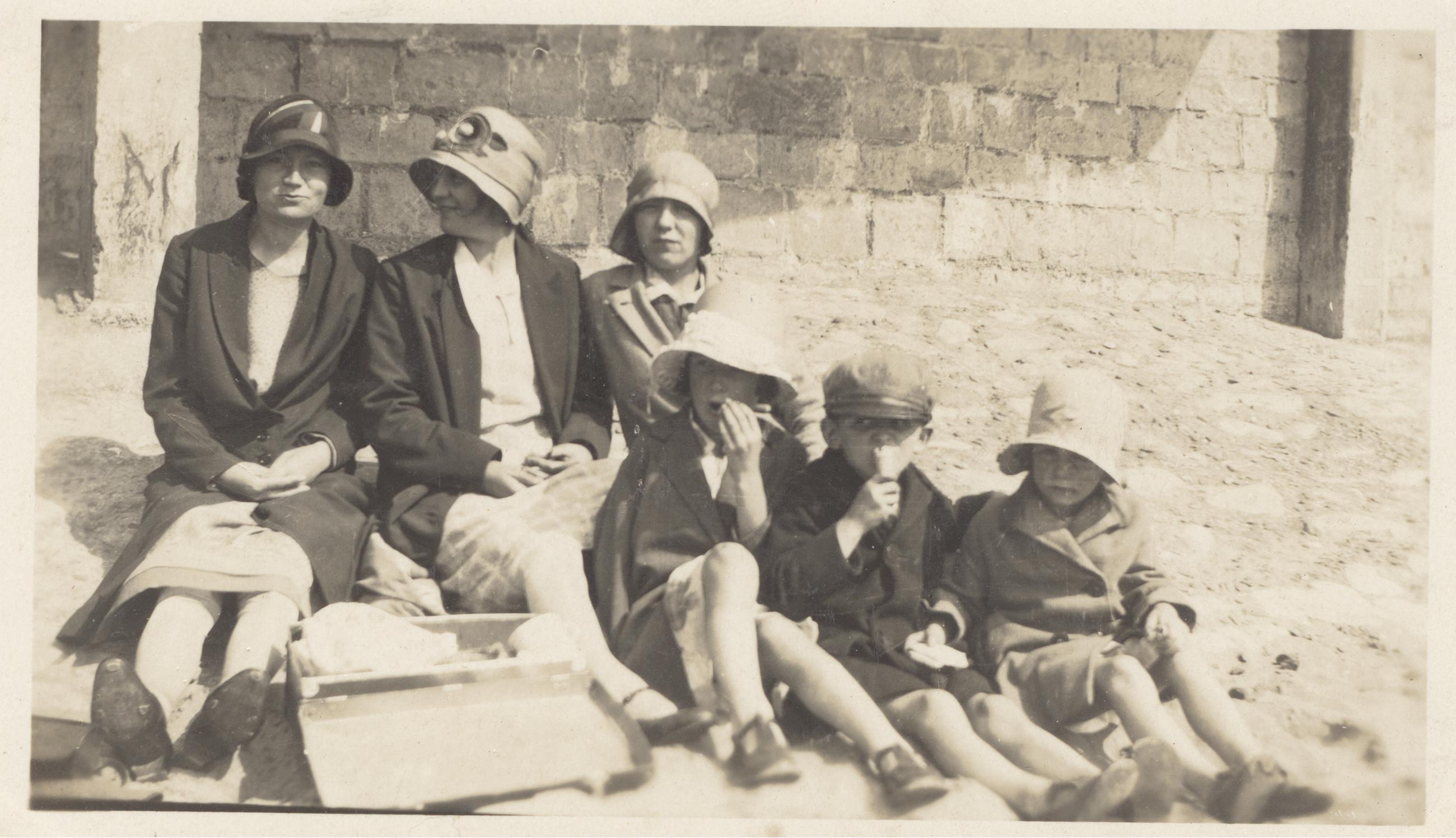 Women and children sat on beach.
