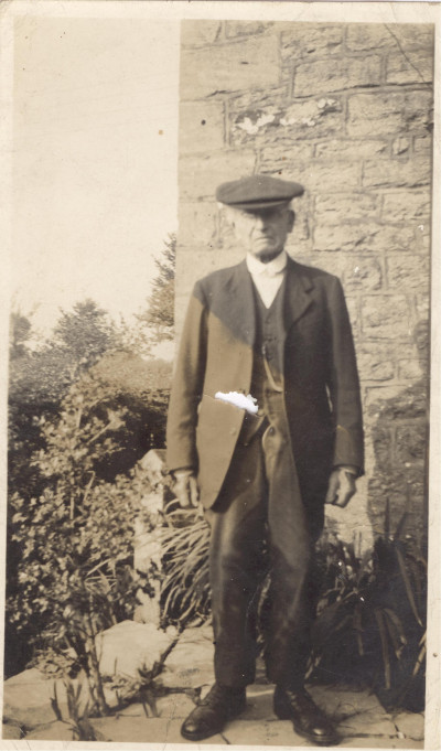 Man in suit & peaked cap.