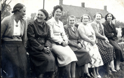 Seven women sitting on wall in Church Street