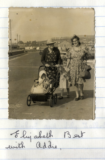Two women with pram and two children at seaside
