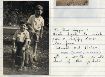Two boys in shorts and sandals  by tree stump, with caption