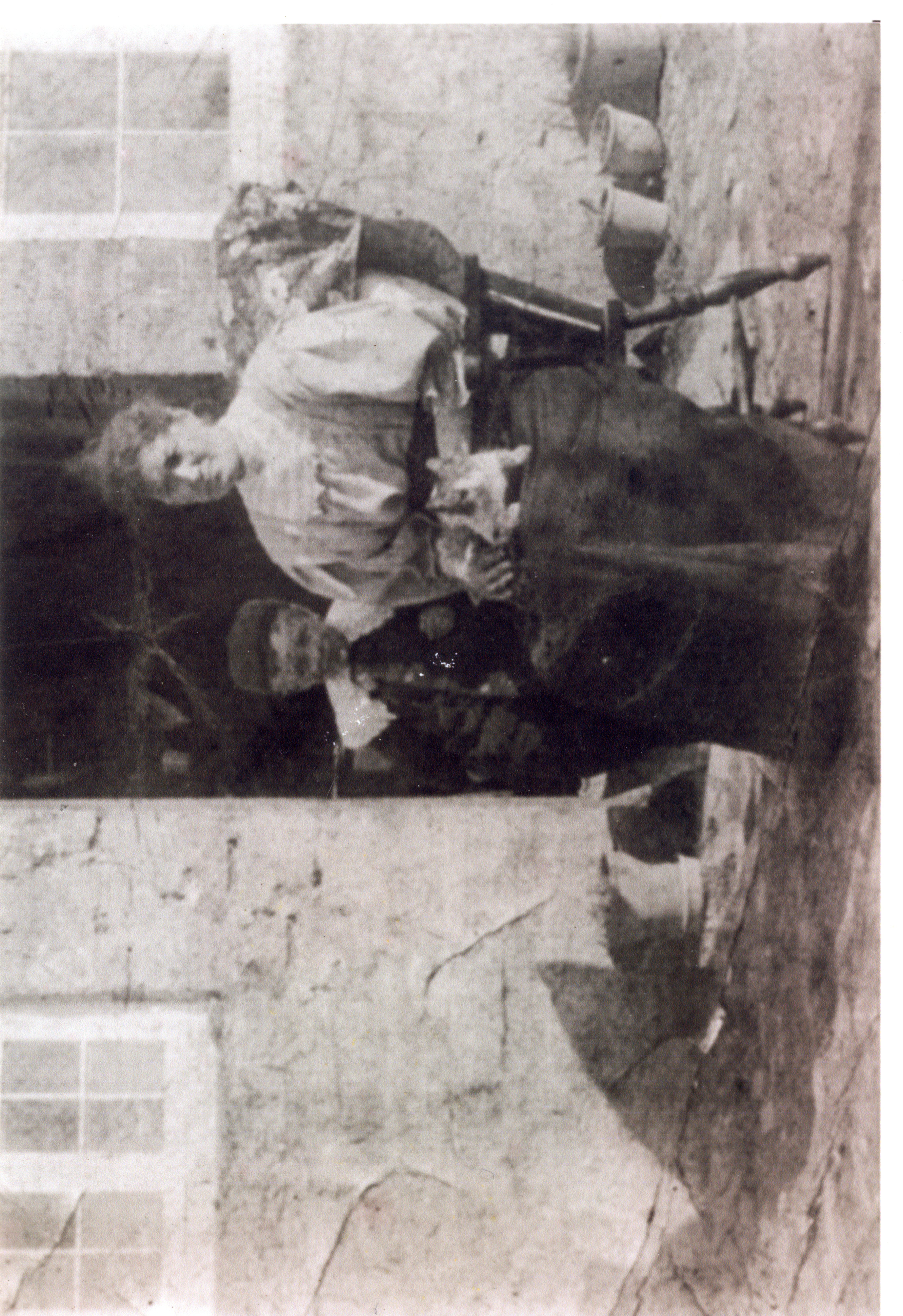 Woman seated and young boy, outside cottage