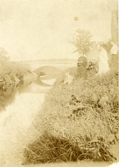 Group of men and women on river bank at Thorney Bridge