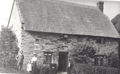 Family group outside thatched cottage